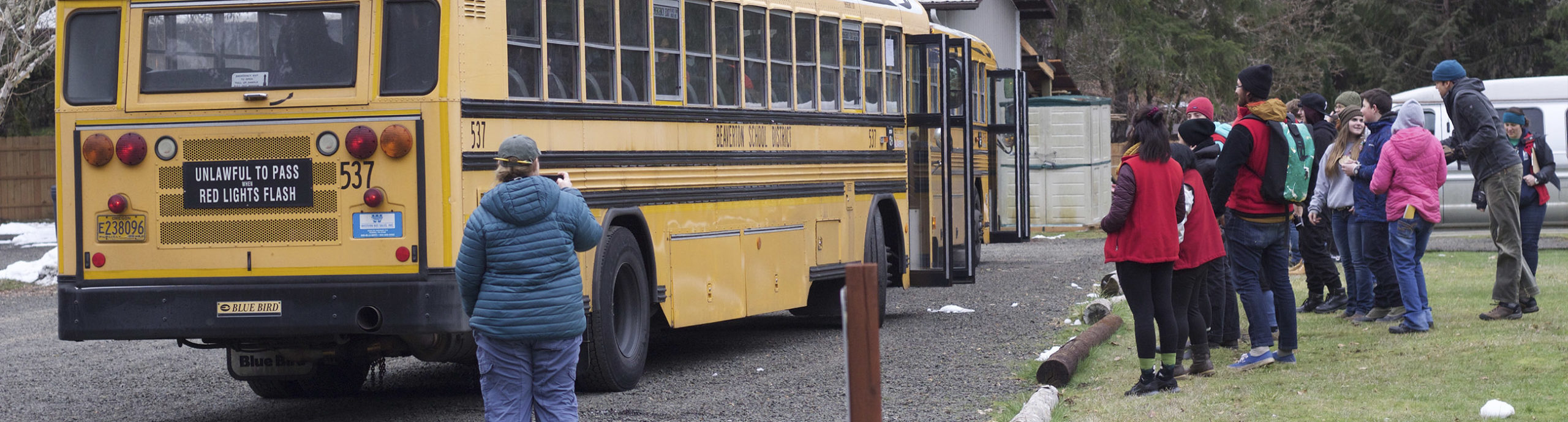 Students waiting in line to board a school bus going to outdoor school