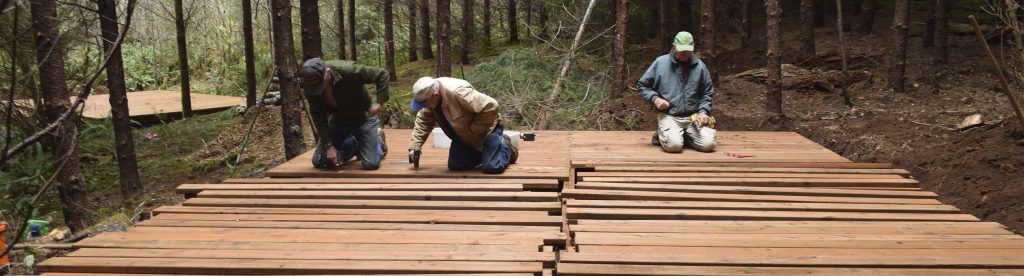 Three men build a platform deck in the forest at Camp Lutherwood Oregon