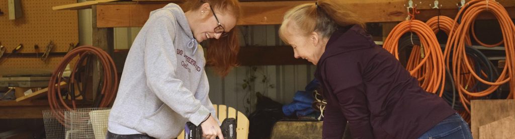 Two women working in a shop with a drill