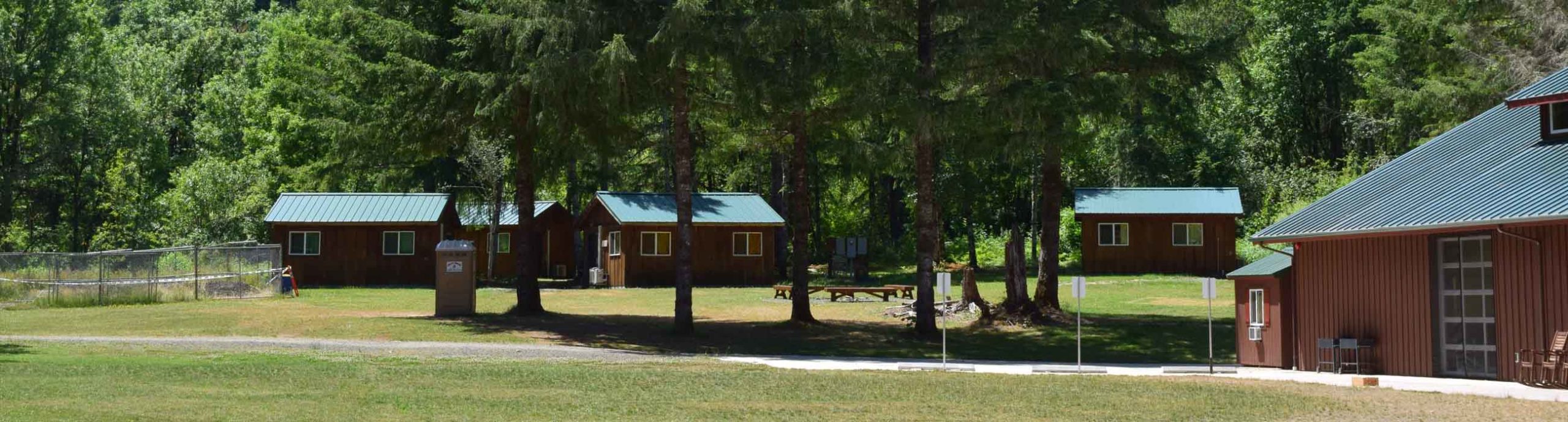 The back field of Camp Lutherwood Oregon with the dining hall in the foreground and upper cabins in the background