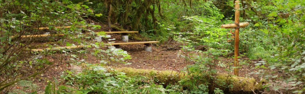 The meeting spot called The Well with three benches and a large cross at Camp Lutherwood Oregon