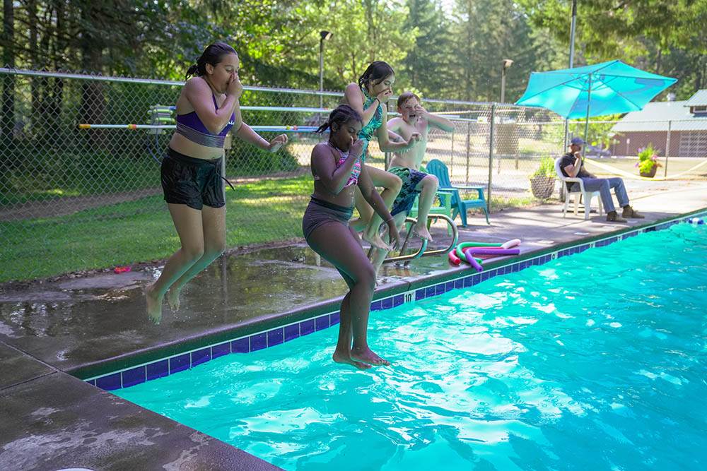 Four middle schoolers jumping in the pool at Camp Lutherwood Oregon