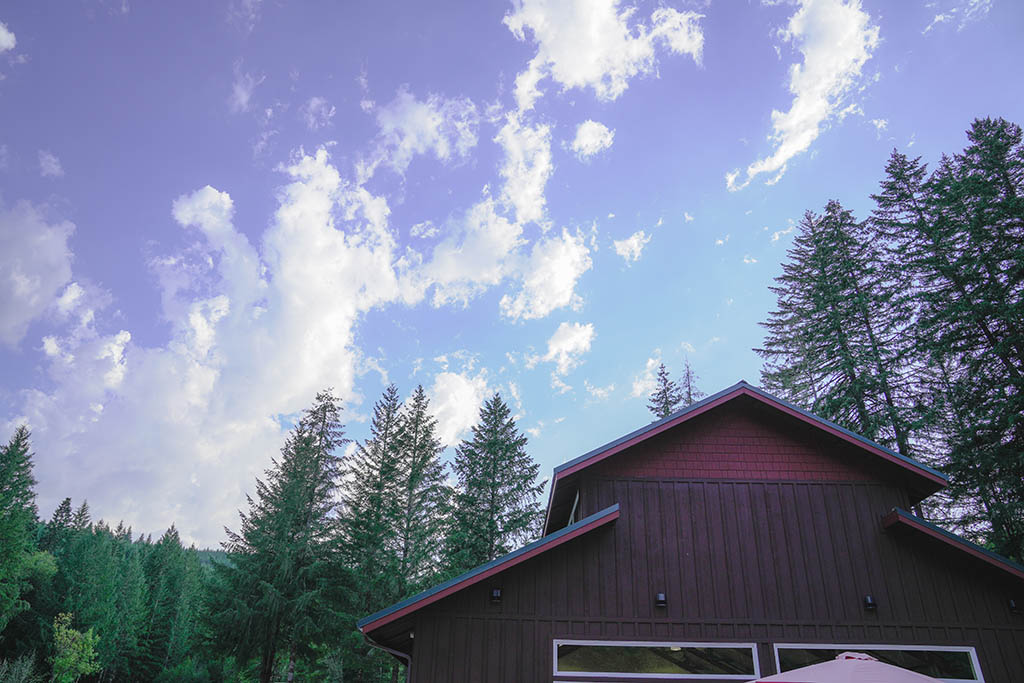 The top of the dining hall at Camp Lutherwood Oregon against a mostly sunny sky and fir trees