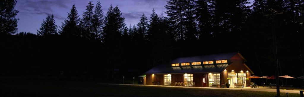 The dining hall lit up and the back field at evening at Camp Lutherwood Oregon