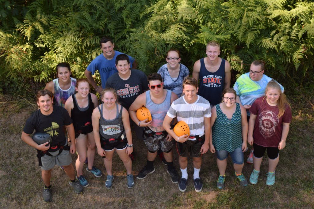 High school campers, some holding rock-climbing helmets, photographed from above at Camp Lutherwood Oregon