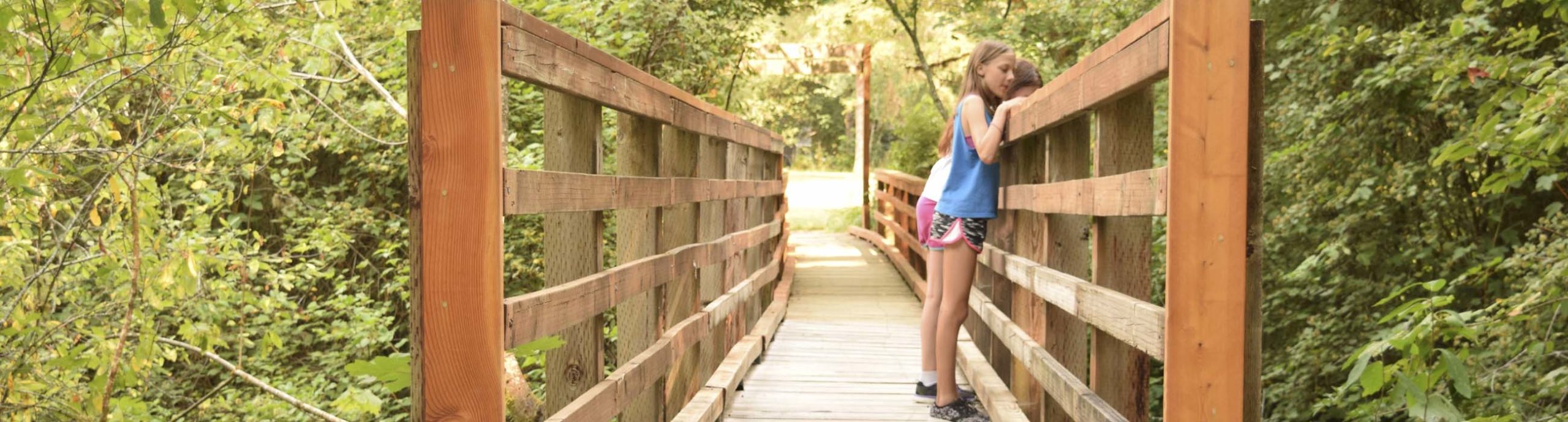 Two girls looking over the edge of the bridge leading into Camp Lutherwood Oregon