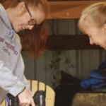 Two women working in a shop with a drill