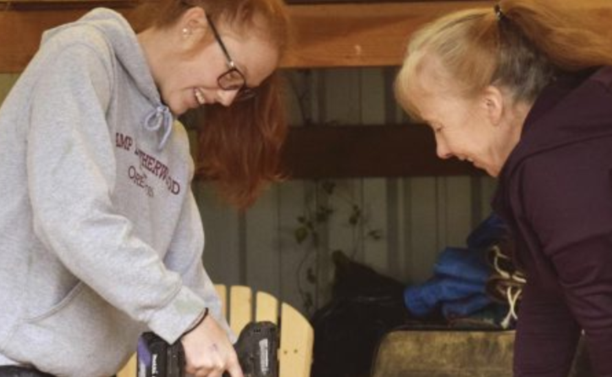 Two women working in a shop with a drill